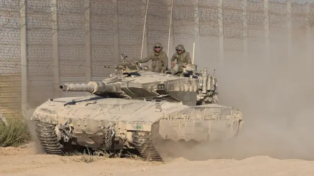 Izraelski tenk sa dvojicom vojnika prolazi pored ojačane ograde.