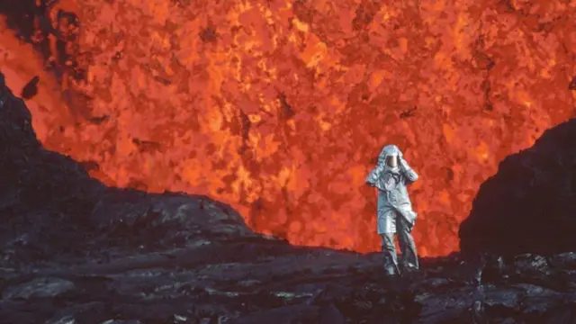 Un homme devant le cratère d'un volcan.
