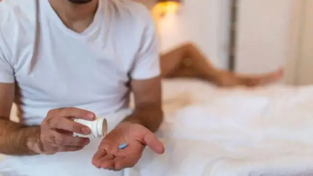 Wani mutum riƙe da ƙwaya mai launin shuɗi