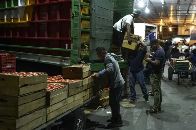 Varios hombres descargan cajas de un camión en La Tiendona, San Salvador, El Salvador, el 13 de febrero de 2023.