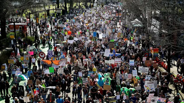 Manifestantes seguram cartazes enquanto marcham pela Naito Parkway durante um protesto “No Kings” contra as políticas do governo do presidente dos EUA, Donald Trump, em Portland, Oregon, em 28 de março de 2026.
