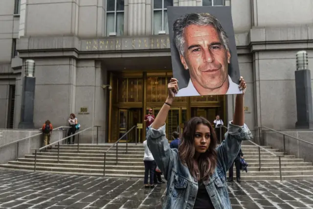  Sebuah kelompok protes bernama "Hot Mess" mengangkat poster Jeffrey Epstein di depan gedung pengadilan federal di Kota New York. 