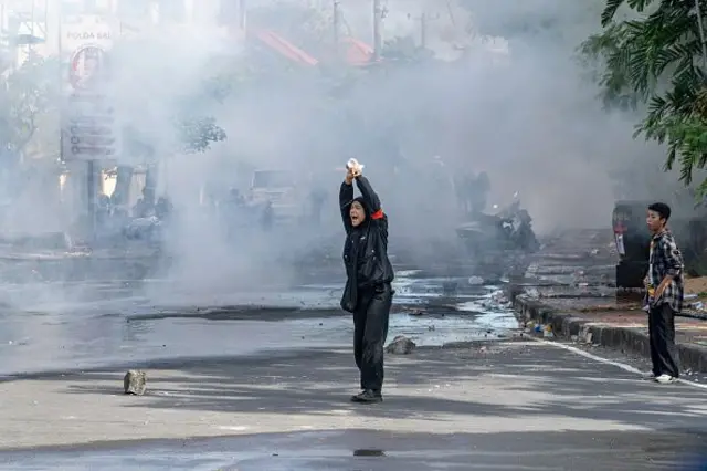 Seorang petugas medis dari sisi pengunjuk rasa memberi isyarat dengan isyarat tangan untuk menghindari ditembak oleh polisi selama protes. 