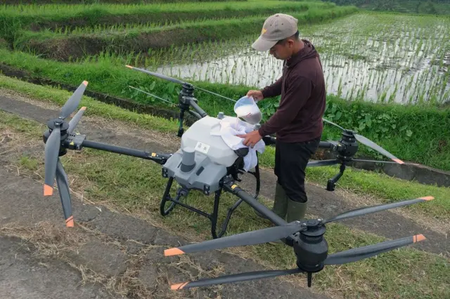 Salah satu petani memasukkan cairan pupuk ke dalam tangki drone.