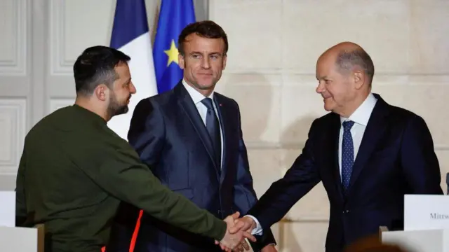 Volodymyr Zelensky asuhuzanya na Olaf Scholz, mu gihe Emmanuel Macron abareba