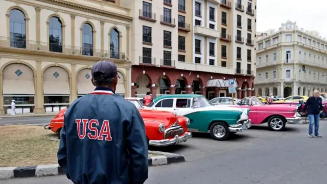 Una persona de espaldas con una chaqueta que dice USA en una calle en Cuba
