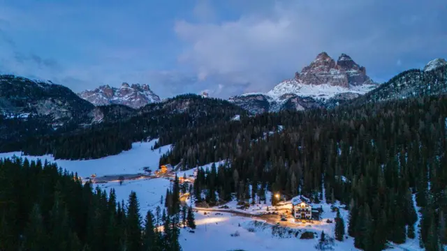 Estación de esquí en Europa con nieve blanca y lisa rodeada de pinos verdes.