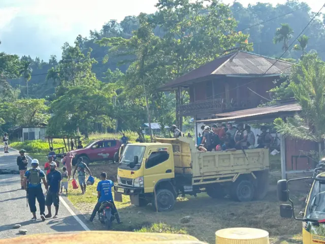 Sejumlah orang naik ke atas truk untuk dievakuasi.
