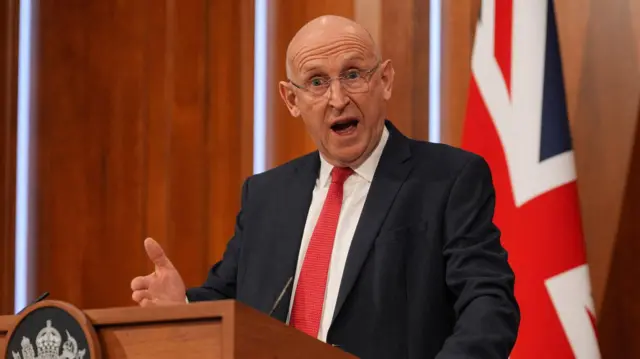 O secretário britânico da Defesa, John Healey, falando à imprensa