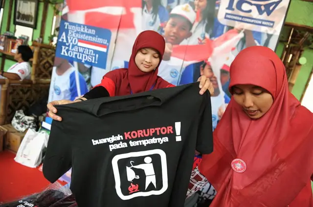 Perempuan aktivis antikorupsi sedang membentangkan kaos kampanye antikorupsi.