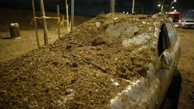 इसराइल पर ईरान के मिसाइल हमले के बाद क्षतिग्रस्त हुई एक कार