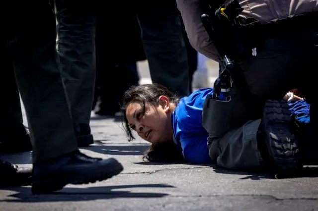 Oficiais do condado de Los Angeles detêm uma mulher durante confronto entre manifestantes e policiais, após várias detenções pelo Serviço de Imigração e Alfândega (ICE), na cidade de Paramount, no condado de Los Angeles, Califórnia