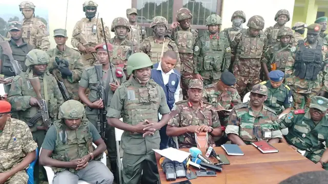 Col Imani Nzenze wa M23 (uhagaze imbere) mu muhango wo gushyikiriza Kibumba, agace kari kuri 25km uvuye i Goma, ingabo z'akarere zizaharinda 