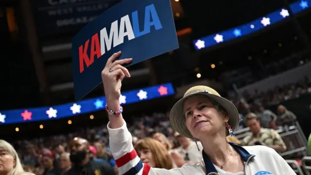 Eleitora democrata segurando um cartaz onde se lê "Kamala"