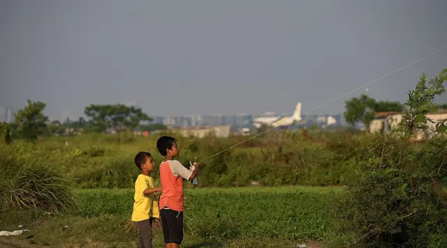 Anak-anak bermain layang-layang di dekat bandara.
