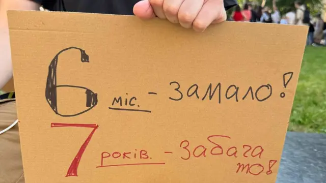 Напис на картонці, який звертає увагу на те, скільки часу на своїх постах пробули Михайло Федорів та Володимир Зеленський 