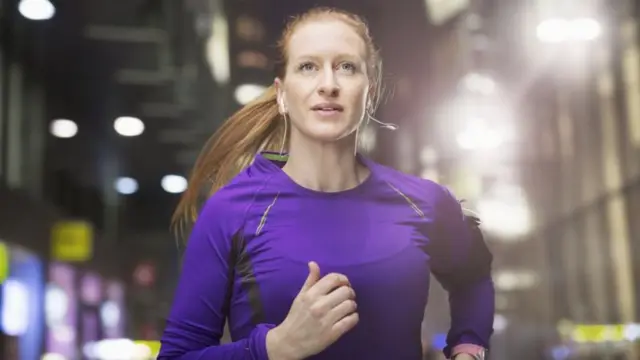 Mulher correndo à noite na ruaroleta sportingbetmeio a prédios