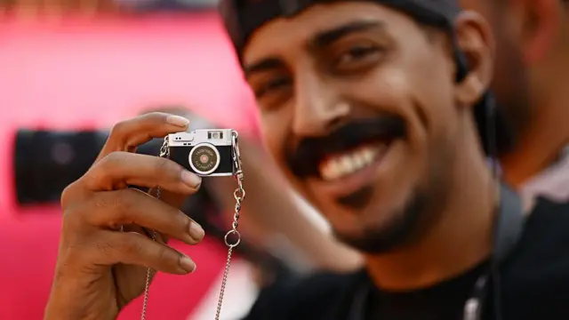 Гість на Міжнародному кінофестивалі Червоного моря у 2025 році показує фотокамеру-брелок