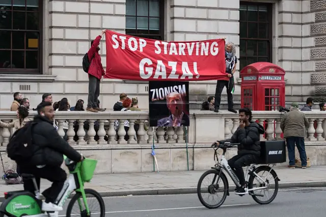 Para demonstran membentangkan spanduk bertuliskan slogan "Hentikan Kelaparan Gaza" dalam sebuah demonstrasi di Parliament Square saat Presiden Amerika Serikat Donald Trump melakukan kunjungan kenegaraan kedua ke Inggris, pada 17 September 2025.