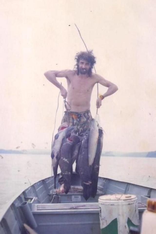 Homem jovem em foto antiga segurando grandes peixes