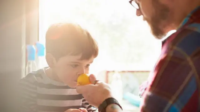 Un niño huele un limón