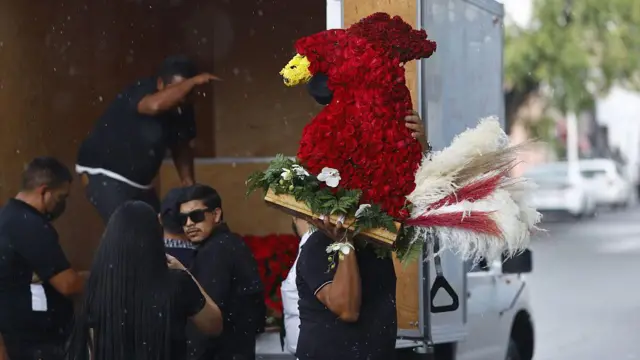 Цветочную композицию в виде красного петуха грузят в машину