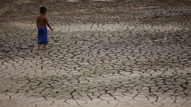 Niño parado en el lecho seco del arroyo de Igarape do Taruma, que desemboca en el Río Negro, en la Amazonía brasileña, durante la sequía de 2023