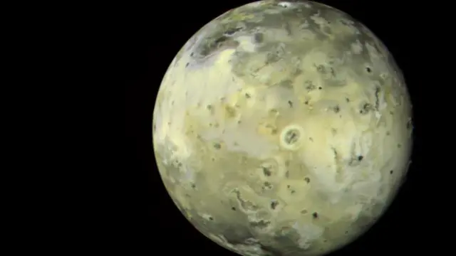 An image of a yellowish sphere against a black background with uneven contours on its surface and a lighter-coloured oval ring near the middle.