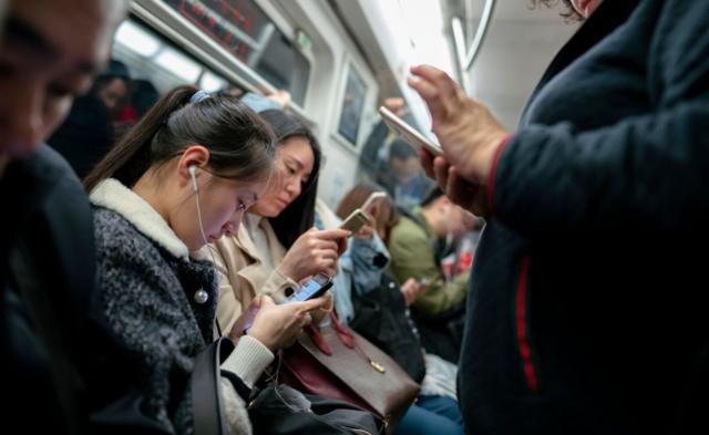 ركاب المترو في الصين ينظرون إلى هواتفهم المحمولة