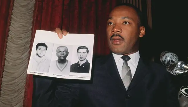 Martin Luther King con la foto de los tres activistas