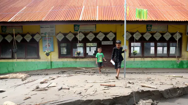 Dua anak bermain halaman sekolah MIN 43 yang rusak dan terendam lumpur di Desa Cot Ara, Kuta Blang, Bireuen, Aceh, Rabu (3/12/2025).