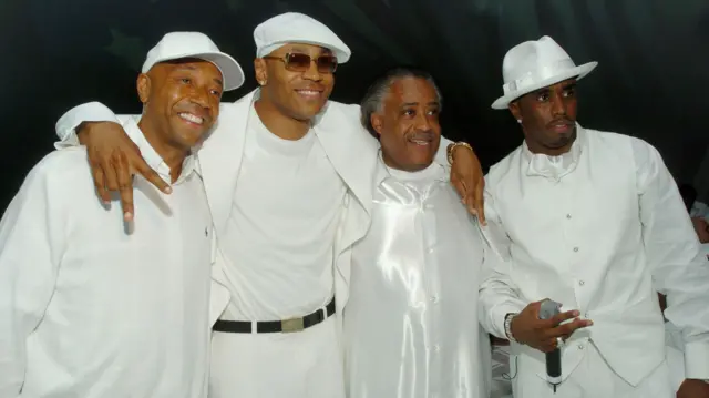 Sean 'Diddy' Combs posando para foto com o produtor musical Russell Simmons, o rapper LL Cool J e o reverendo Al Sharpton. Todos estão vestidosdragon bet sign up offerbranco