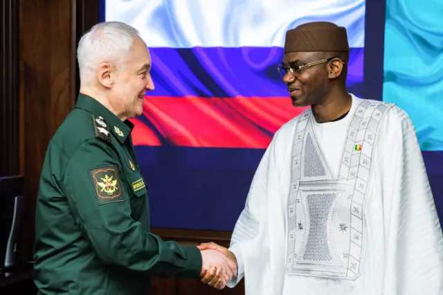 Камара и Белоусов жмут руки на фоне флага России 