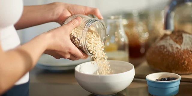 Une femme verse des flacons d'avoine dans un petit bol