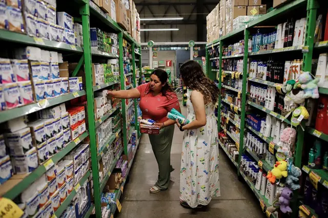 Ada Bell Baquedano (L), madre de Emerson Colindres, compra con su hija, Alison Colindres, en un supermercado en Marcovia, Honduras, el 24 de junio de 2025. Emerson acaba de terminar la escuela secundaria cuando fue enviado de regreso a Honduras por Estados Unidos, un país que había llamado hogar desde que tenía ocho años. Ahora, como muchos otros jóvenes deportados que emigraron a Estados Unidos de niños, está luchando por adaptarse a la vida en una patria que le resulta extraña. Su madre y su hermana vivieron con él en Cincinnati y regresaron a Honduras seis días después de que él llegó en un vuelo chárter de deportación. (Foto de Jorge CABRERA / AFP) (Foto de JORGE CABRERA/AFP a través de Getty Images)