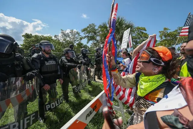 Policiais de Palm Beach impedem manifestantes de cruzar uma ponte para a casa do presidente Donald Trump em Mar-a-Lago durante o protesto "No Kings" em 14 de junho de 2025 em West Palm Beach, Flórida