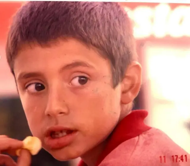 Juan Cuatrecasas, criança, olha para trás enquanto come um salgadinho