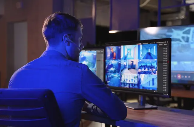 Ilustrasi petugas sekuriti memantau situasi dari ruang kontrol.