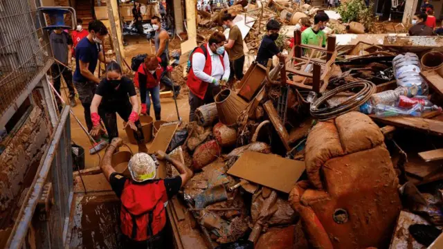 泥が流れ込んだ建物の地下を片付ける消防隊員とボランティア（3日、バレンシア州アルファファル）