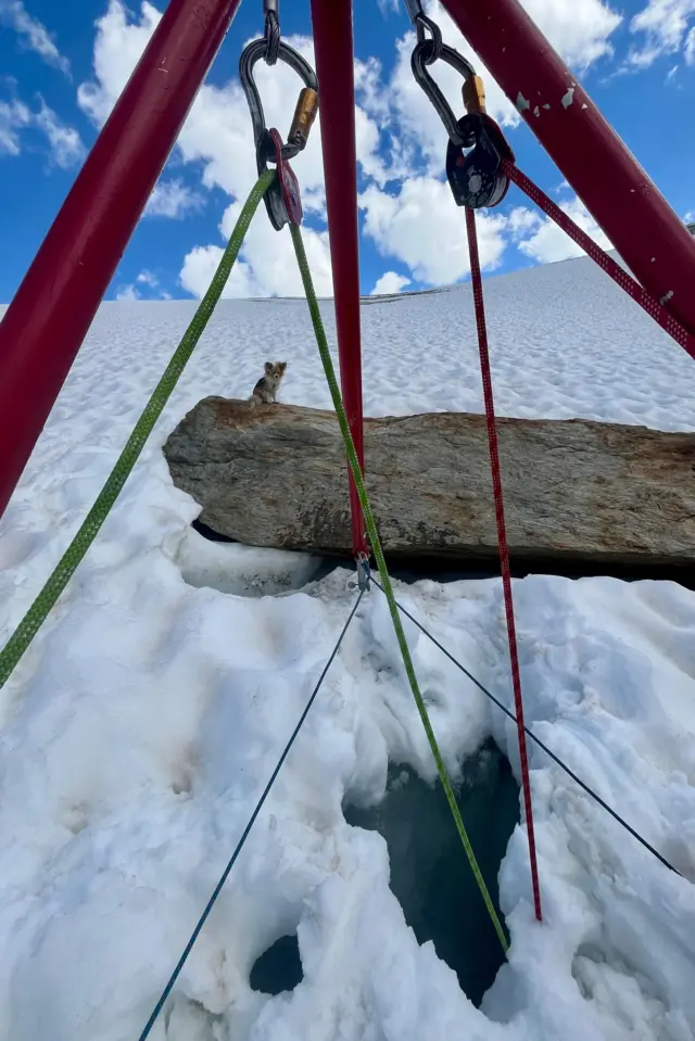 La estructura de anclaje construida por los rescatistas con cuerdas verdes y rojas sobre el agujero.