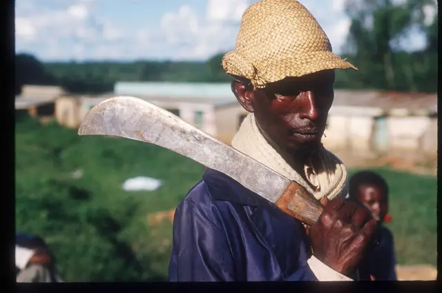 Руанданын Рукумбеллдеги качкындар лагерин жанында мачета көтөрүп жүргөн киши, 1994-ж. май айы. 1994-ж. апрелинде Руандада Рукара католик миссиясында жүздөгөн тутси этносундагылар кыргынынга кабылган.