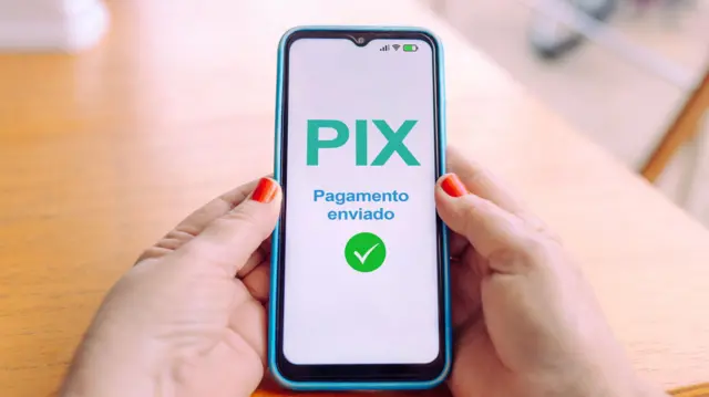 Mãos segurando um celular em que na tela se lê "Pix enviado"
