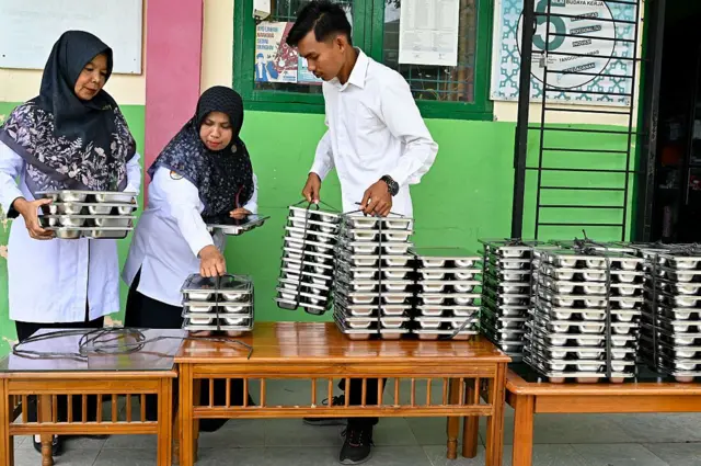 Para guru mengumpulkan nampan makanan untuk siswa mereka, yang disediakan oleh program makanan gratis pemerintah Indonesia, di sebuah sekolah dasar di Darul Kamal, provinsi Aceh pada 13 Oktober 2025