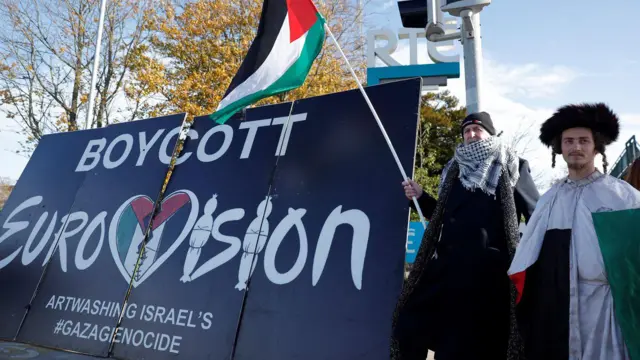 Manifestantes pró-palestinos seguram bandeiras e cartazes em frente aos estúdios da emissora pública irlandesa RTÉ