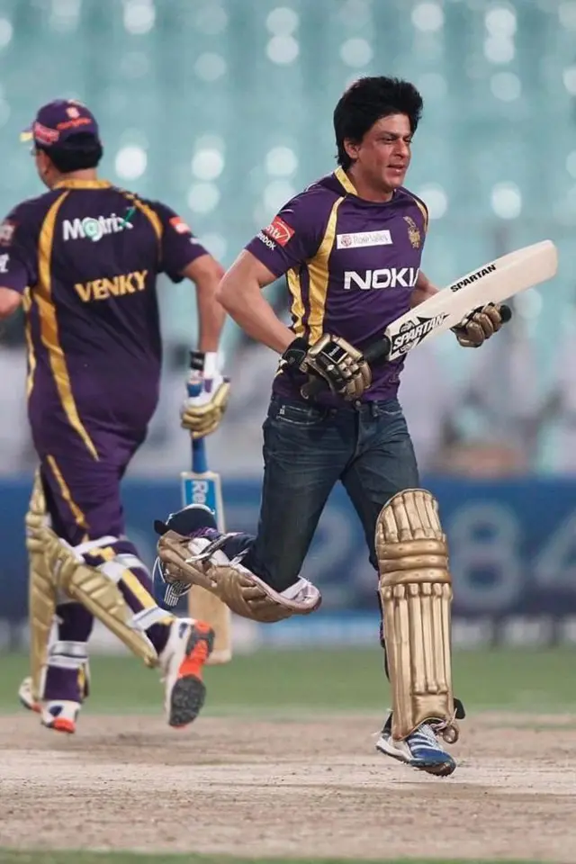 क्रिकेट पिच पर पैड पहनकर बैट लेकर दौड़ते शाहरुख ख़ान