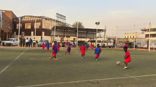 مجموعة من اللاعبين من قصار القامة وهم يلعبون كرة القدم في الملعب.