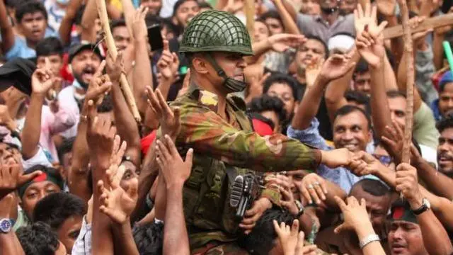 शेख़ हसीना के देश छोड़ने की ख़बर के बाद सैनिकों के आसपास आम लोग ख़ुशी से झूम उठे