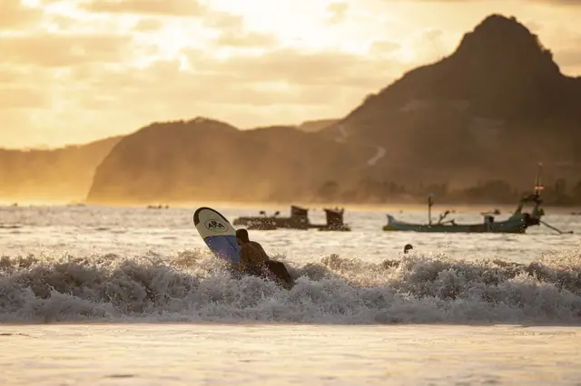 Wisatawan berselancar di Pantai Selong Belanak pada 7 Oktober 2025 di Lombok, Indonesia.