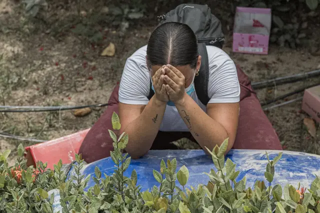 Una mujer está sobre sus rodillas, hincada rezando