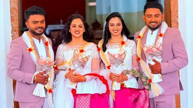 Two newly wed couples stanind infront of a door